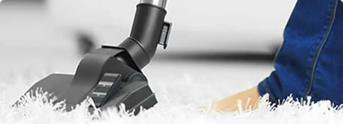 Close-up of a professional vacuuming a white carpet in Hartford.